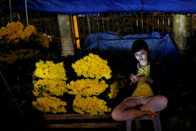 A woman at a flower stall at a night market in Hanoi, Vietnam.